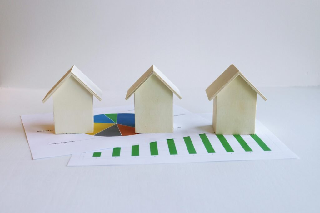 Wooden model houses on graphs depict real estate market analysis and trends.